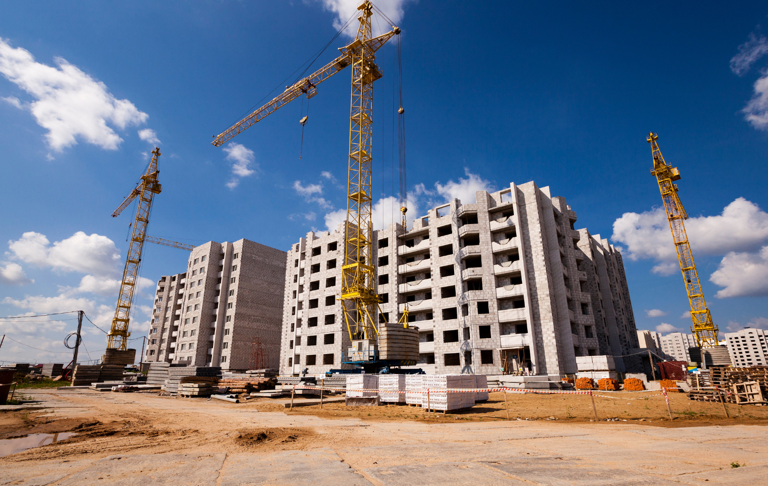 Tower cranes and stacked building materials at a multi-family apartment construction site